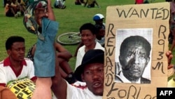 Un sympathisant du Congrès national africain (ANC) tient une affiche anti-président Lucas Mangope et une jambe de mannequin lors d'un rassemblement à Mmabatho le 13 mars 1995.