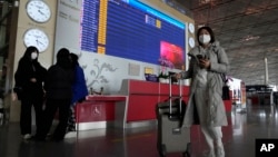 Passengers pass near a flight departure board in a Capital airport terminal in Beijing, Dec. 13, 2022. 