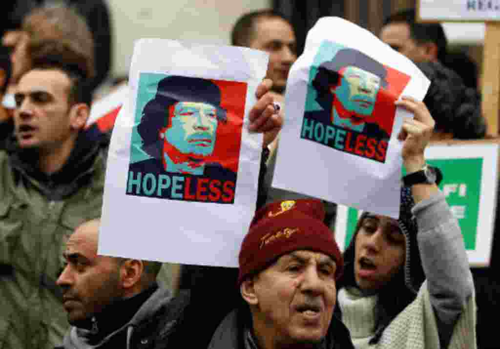 Demonstrators hold up posters depicting Libya's Moammar Gadhafi during a protest in Brussels, February 25, 2011