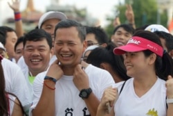 FILE - Lt. Gen. Hun Manet, center, of the Royal Cambodian Armed Forces (RCAF) and the first son of Cambodian Prime Minister Hun Sen, smiles before the start of the international half-marathon in front of Royal Palace in Phnom Penh, Cambodia, Sunday, June 12, 2016. Several thousands of Cambodians and foreigners took part in the race, marking the birthday of Queen Monineath Sihanouk on June 18. (AP Photo/Heng Sinith)