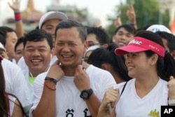 FILE - Lt. Gen. Hun Manet, center, of the Royal Cambodian Armed Forces (RCAF) and the first son of Cambodian Prime Minister Hun Sen, smiles before the start of the international half-marathon in front of Royal Palace in Phnom Penh, Cambodia, Sunday, June 12, 2016. Several thousands of Cambodians and foreigners took part in the race, marking the birthday of Queen Monineath Sihanouk on June 18. (AP Photo/Heng Sinith)