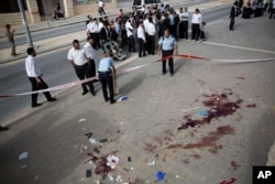 Israeli police officers inspect the scene of a stabbing attack in Beit Shemesh, central Israel, Oct. 22, 2015. Police say two Palestinians stabbed an Israeli man in the city of Beit Shemesh after attempting to board a bus ferrying children to school.