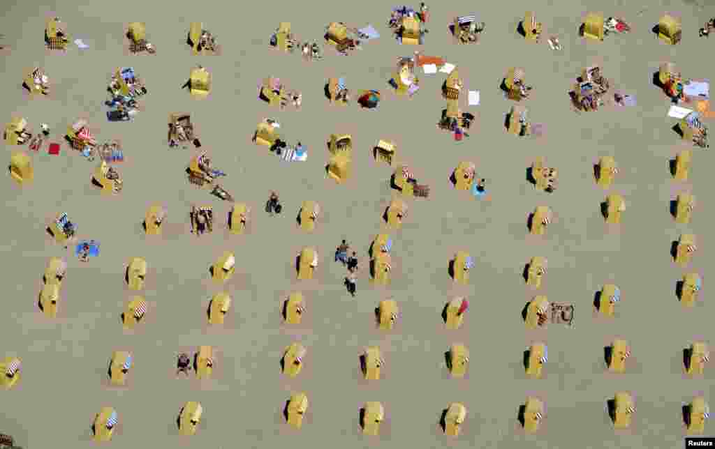 People take a sunbath in beach chairs at a beach in Travemuende by the Baltic Sea, Germany.