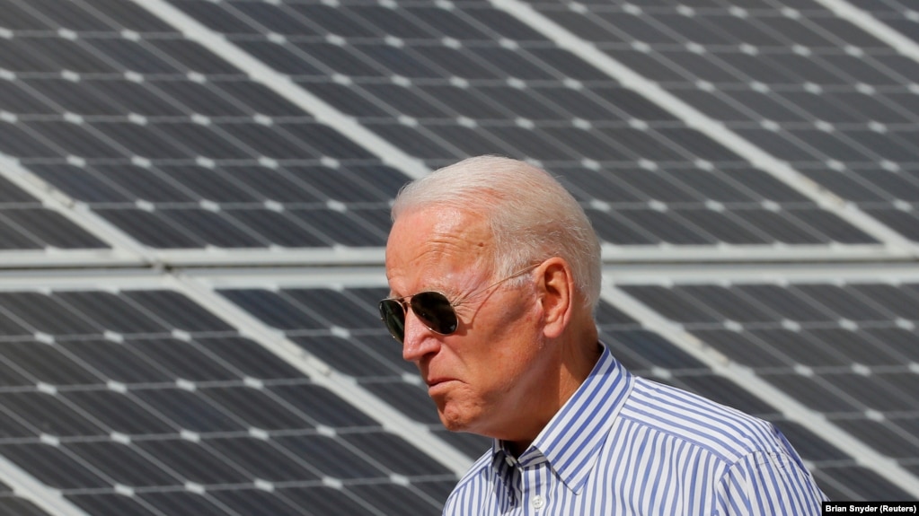 资料照片：2019年6月4日，在美国新罕布什尔州普利茅斯，拜登参观“普利茅斯地区可再生能源计划”时走过太阳能电池板。民主党人拜登在2020年11月当选美国总统。(photo:VOA)