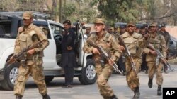 Tentara Pakistan bergegas menuju lokasi ledakan bom di Peshawar, Pakistan (18/2). Seorang militan menyamar sebagai polisi dan mengenakan jaket untukmeledakkan bom saat menyerang kantor seorang pejabat politik senior Pakistan. (AP Photo/Mohammad Sajjad)