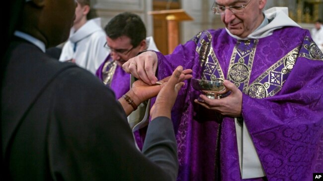 En París, fieles reciben la sagrada comunión en sus manos durante una misa celebrada en la iglesia de San Francois Xavier, el domingo 1 de marzo de 2020. El arzobispo de París ha pedido a todos los párrocos de la capital francesa que cambien la forma en que administran la comunión para contrarrestar la propagación del coronavirus. El arzobispo dijo que un sacerdote de París dio positivo por el virus el viernes después de regresar de Italia.