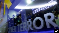 Members of media are reflected on the door of Cyber Terror Response Center as they wait to enter the lab at National Police Agency in Seoul, South Korea, March 21, 2013.