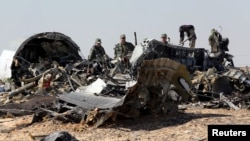 Military investigators from Russia stand near the debris of a Russian airliner at the site of its crash at the Hassana area in Arish city, north Egypt, Nov. 1, 2015. 