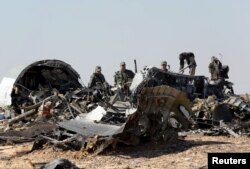FILE - Military investigators from Russia stand near the debris of a Russian airliner at the site of its crash at the Hassana area in Arish city, north Egypt, Nov. 1, 2015.