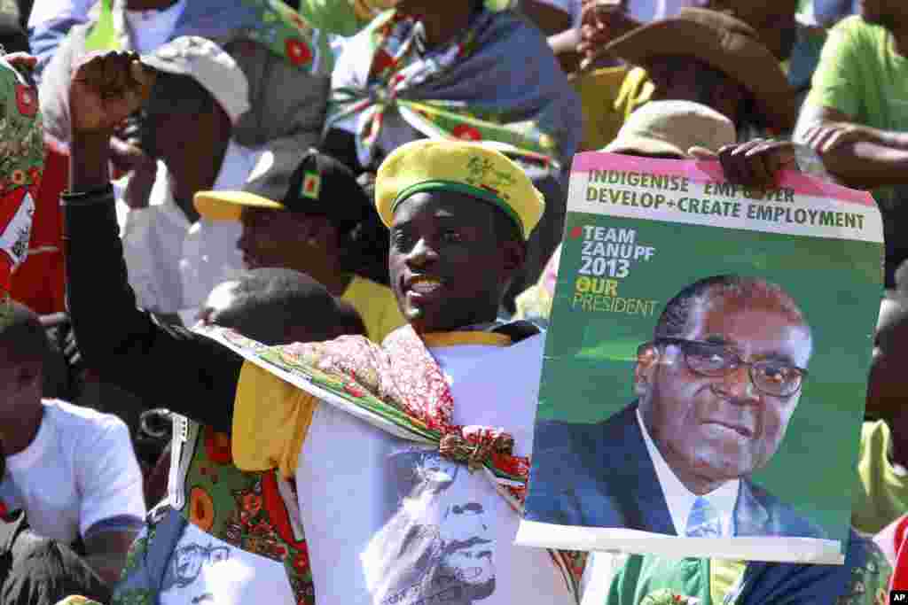 Mfuasi wa rais Robert Mugabe akibeba bango la rais wakati wa sherehe za kuapishwa kwake mjini Harare, August 22, 2013.