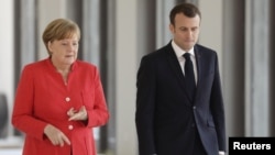 German Chancellor Angela Merkel and French President Emmanuel Macron are on their way to a news conference at the building site of the Humboldt Forum in Berlin, April 19, 2018. 