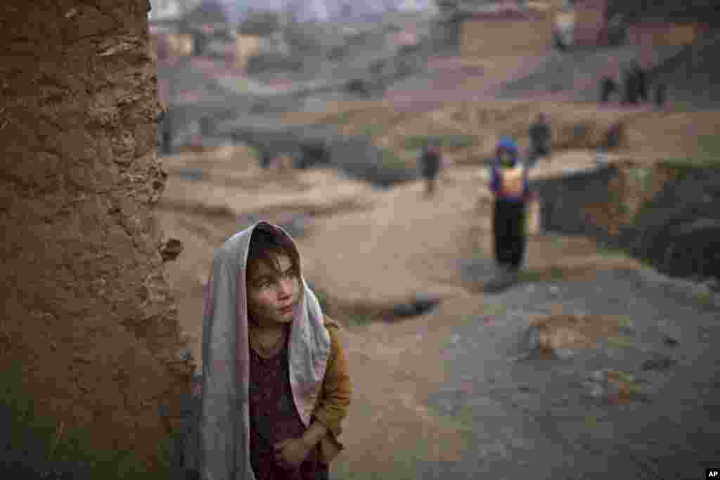 Afghan refugee Sayma Naseeb, 4, stands by the doorway of her family's mud house in a poor neighborhood on the outskirts of Islamabad, Pakistan.