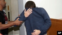 FILE - A 19-year-old dual U.S.-Israeli citizen covers his face as he is brought to court in Rishon Lezion, Israel, March 23, 2017. Israeli police said they have arrested a Jewish Israeli man who is the prime suspect behind a wave of bomb threats against Jewish community centers and other institutions in the United States. 