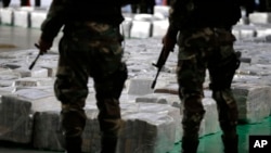 FILE - Police officers stand guard over seized cocaine they present to the press in Lima, Peru, Sept. 1, 2014. 