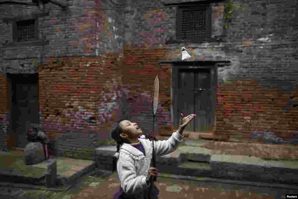 A girl plays badminton along the street outside old houses in the ancient city of Bhaktapur, near Nepal&#39;s capital Kathmandu.