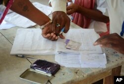 An Indian polling official helps a woman put her thumb imprint before proceeding to cast her vote at a polling station at Samastipur district, in India’s eastern state Bihar, October 12, 2015.