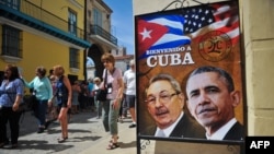 Tourists walk next to a poster of Cuban President Raul Castro and US president Barack Obama in Havana, on March 18, 2016. 