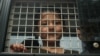 FILE - Ethnic Uighur Muslim boy stands inside a police van in Khlong Hoi Khong of southern Songkhla province, Thailand. He was in a group of 200 people rescued from a human trafficking camp.