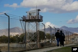 A couple walks past a U.N. guard post at the fence that divides the Greek and Turkish Cypriot areas, as they stroll at the Turkish Cypriot northern part of the divided capital Nicosia in the eastern Mediterranean island of Cyprus, Jan. 11, 2017.