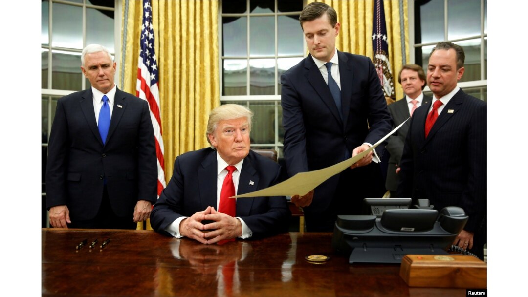 FILE - White House Staff Secretary Rob Porter gives U.S. President Donald Trump, flanked by Vice President Mike Pence, left, and Chief of Staff Reince Priebus, right, the document to confirm Secretary of Defense James Mattis.
