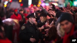 A New York police officer helps manage the crowd during the hours leading up to the annual New Year's Eve celebration in Times Square, Dec. 31, 2015, in New York. 