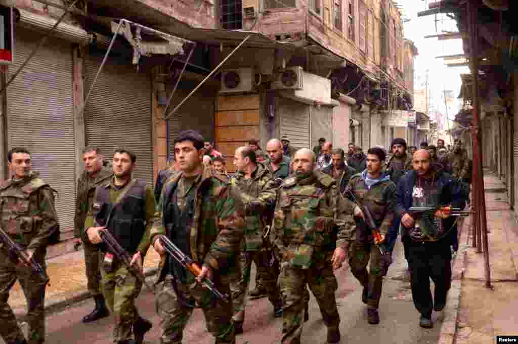 Syrian government forces walk along a street in the al-Sabaa Bahrat district of Aleppo, February 20, 2012.
