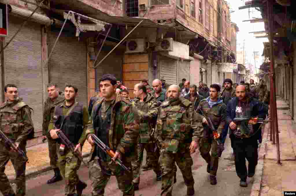 Syrian government forces walk along a street in the al-Sabaa Bahrat district of Aleppo, February 20, 2012. 