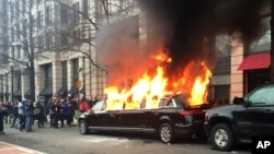 FILE - Protesters set a parked limousine on fire in downtown Washington during the inauguration of President Donald Trump, Jan. 20, 2017. 