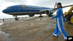 FILE - A Vietnam Airlines employee walks out to greet a newly delivered Boeing 777-200ER at Noi Bai airport in Hanoi, Vietnam on Sunday Sept. 19, 2004. (AP Photo/Richard Vogel)