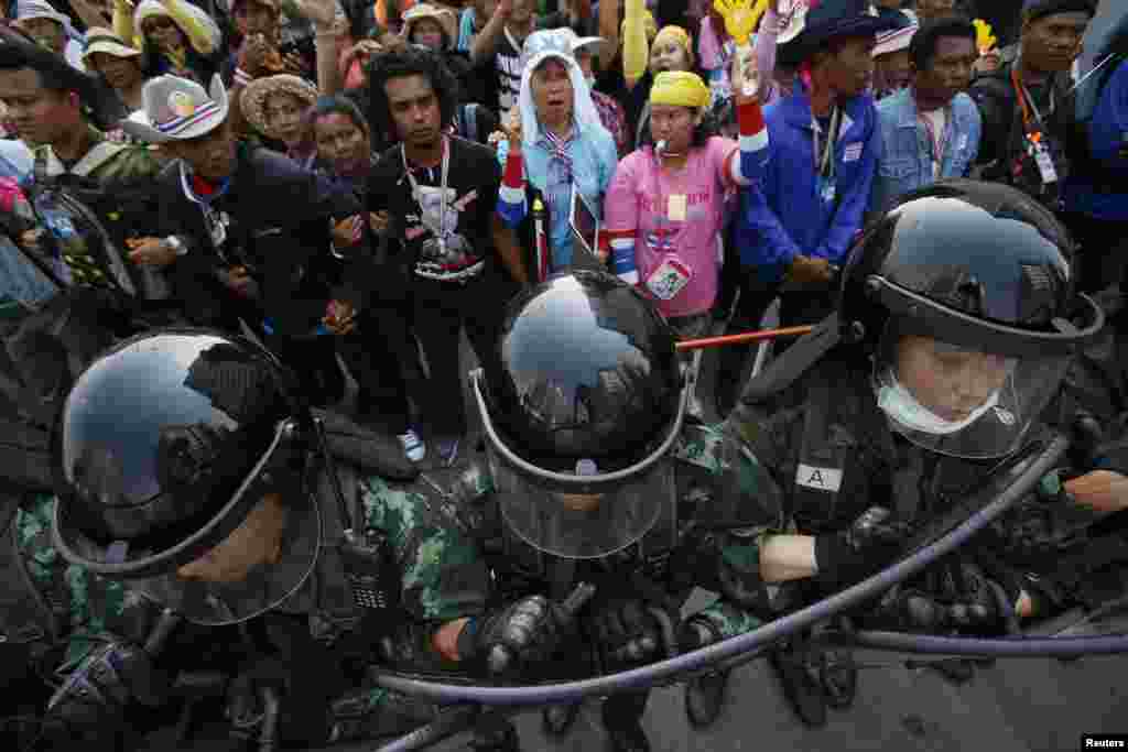 Soldiers hold their shields as officials leave a government office where Prime Minster Yingluck Shinawatra had been holding a meeting as anti-government protesters gather outside in Bangkok, Feb. 3, 2014.