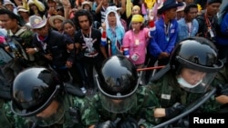 2014年2月3日，在泰国首都曼谷的警察在官员开完会要离开英拉总理的政府办公大楼期间加强戒备，而政府办公大楼外面反政府抗议群众继续示威。
