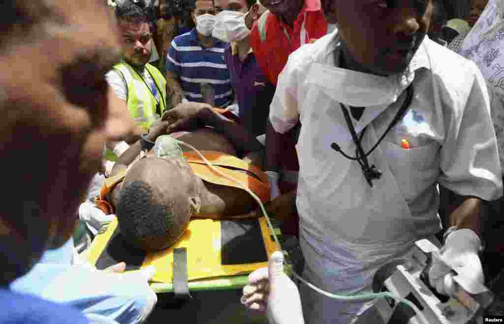 Paramedics assist a construction worker who was rescued from a collapsed building in the Kariakoo district of central Dar es Salaam, Tanzania, March 29, 2013. 