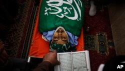 A Palestinian reads from the Quran during the funeral of Munir Badarin, who was shot during clashes with Israeli soldiers in the West Bank village of Samoa, south of Hebron, July 14, 2014.