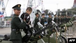 Binh sĩ Quân đội Giải phóng Nhân dân Trung Quốc bế một bé trai tại căn cứ hải quân Stonecutter Island ở Hồng Kông. Bắc Kinh khẳng định rằng duy trì hòa bình và thúc đẩy cho sự phát triển chung của thế giới là tôn chỉ của chính sách ngoại giao của Trung Qu