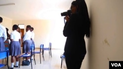 Gloria Iribagiza snaps photos in a classroom. (Photo: C. Oduah for VOA)