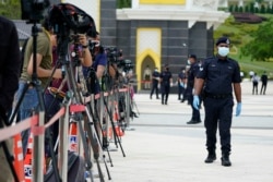 FILE - Police wearing a face mask to help curb the spread of the coronavirus guard media outside National Palace in Kuala Lumpur, Malaysia, Sunday, Oct. 25, 2020.