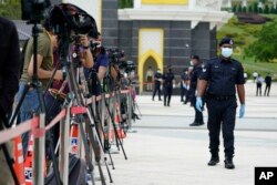 FILE - Police wearing a face mask to help curb the spread of the coronavirus guard media outside National Palace in Kuala Lumpur, Malaysia, Sunday, Oct. 25, 2020.