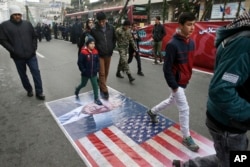 Iranians march on a portrait of U.S. President Donald Trump and the picture of U.S. flag in an annual rally commemorating the anniversary of the 1979 Islamic revolution, which toppled the late pro-U.S. Shah, Mohammad Reza Pahlavi, in Tehran, Iran, Feb. 10
