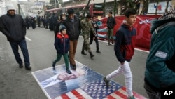 Des Iraniens marchent sur le portrait de Donald Trump et le drapeau des Etats-Unis, le 10 février a Teheran. 