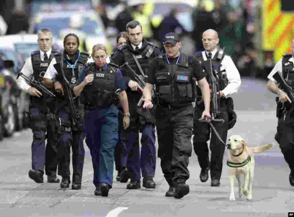 Un grupo de policías británicos caminan con un perro policía en la zona acordonada del área del Puente de Londres donde el sábado por la noche un ataque dejó varios muertos y decenas de heridos. Junio 4 2017.&nbsp;