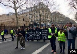 "Yellow vest" protesters in Paris carry a banner calling for rights for the unemployed. (L. Bryant/VOA)