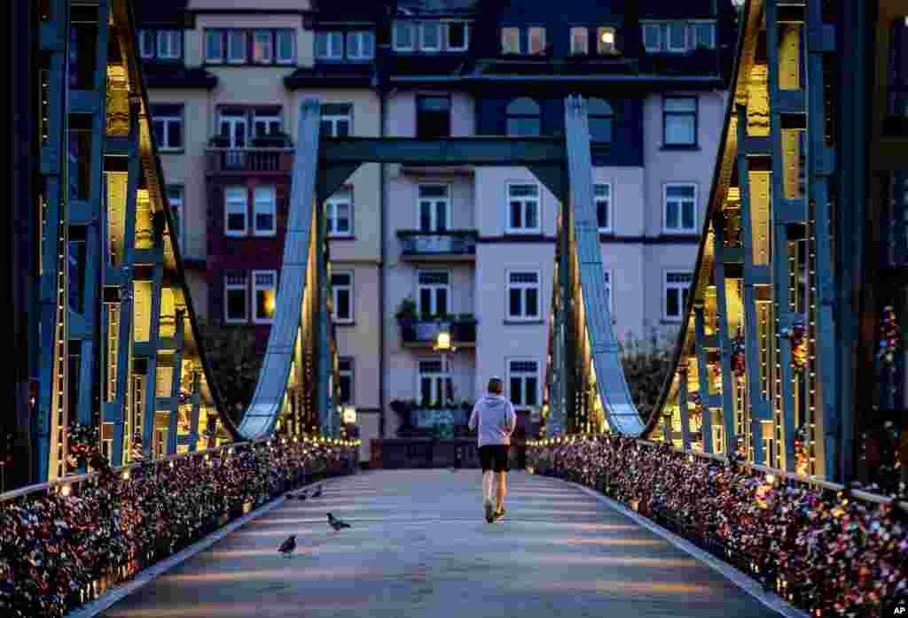 A man runs over the &quot;Eiserner Steg&quot; pedestrian bridge over the river Main in Frankfurt, Germany.
