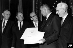 FILE - U.S. President Lyndon B. Johnson holds the signed document of the Voting Rights Act of 1965 as he chats with Sen. Everett Dirksen, R-Ill., in the President's Room in Washington, D.C., Aug. 6, 1965.