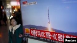 2016年２月７日，韩国首尔火车站，一位旅客走过正在显示北朝鲜发射远程火箭新闻的电视屏幕。