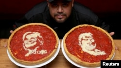 El cocinero Fabián Martínez posa con pizzas decoradas con imágenes de Hillary Clinton y Donald Trump en Giordano' Pizzeria, en Chicago, Illinois.