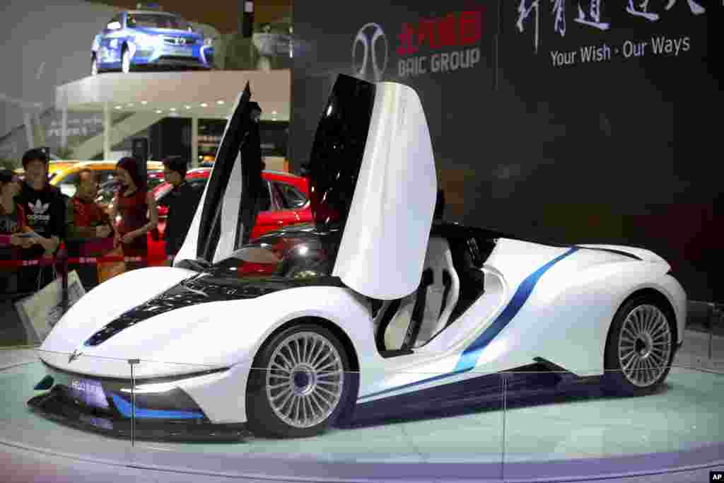 Visitors look at an Arcfox-7 electric sports car by Chinese automaker BAIC on display at the Beijing International Automotive Exhibition.