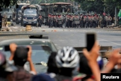 FILE - Police stand on a road during an anti-coup protest in Mandalay, Myanmar, March 3, 2021.