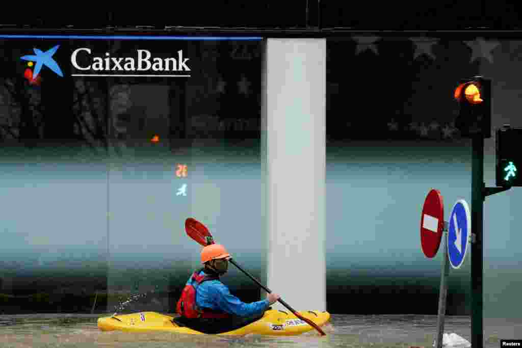 A man rides a kayak on a flooded road, following heavy rainfall in Pamplona, Spain. 