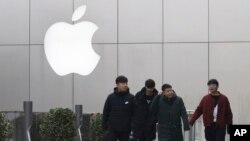 Chinese men walk past the Apple logo in Beijing, China, Thursday, Jan. 3, 2019. (AP Photo/Ng Han Guan)