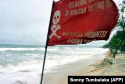 Bendera peringatan berkibar saat gelombang tinggi mencapai pantai di Kuta, Bali, 2 Maret 2006. (Foto: AFP/Sonny Tumbelaka)